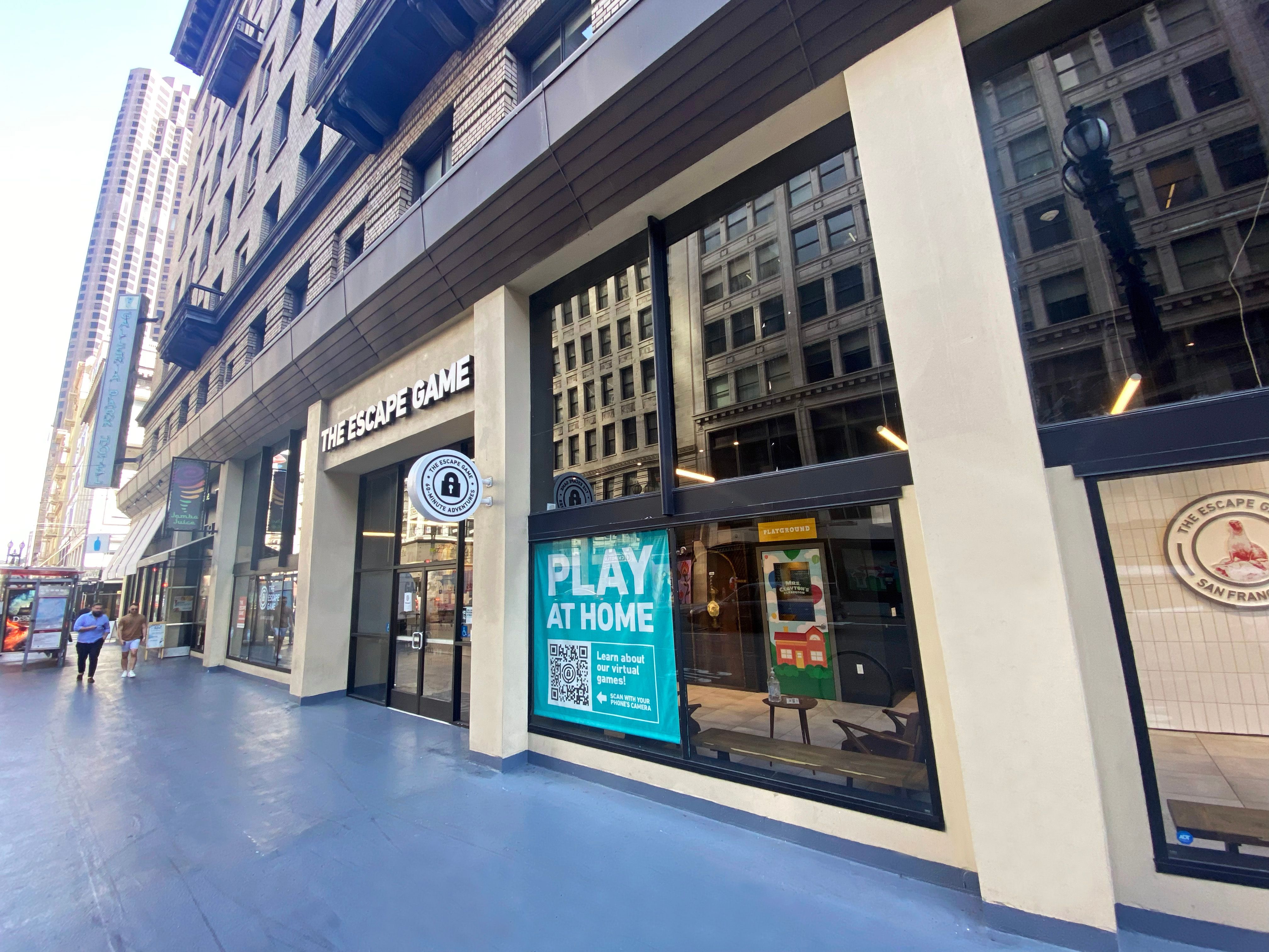 Exterior view of "The Escape Game" location, featuring large windows, signage, and a promotional window display.