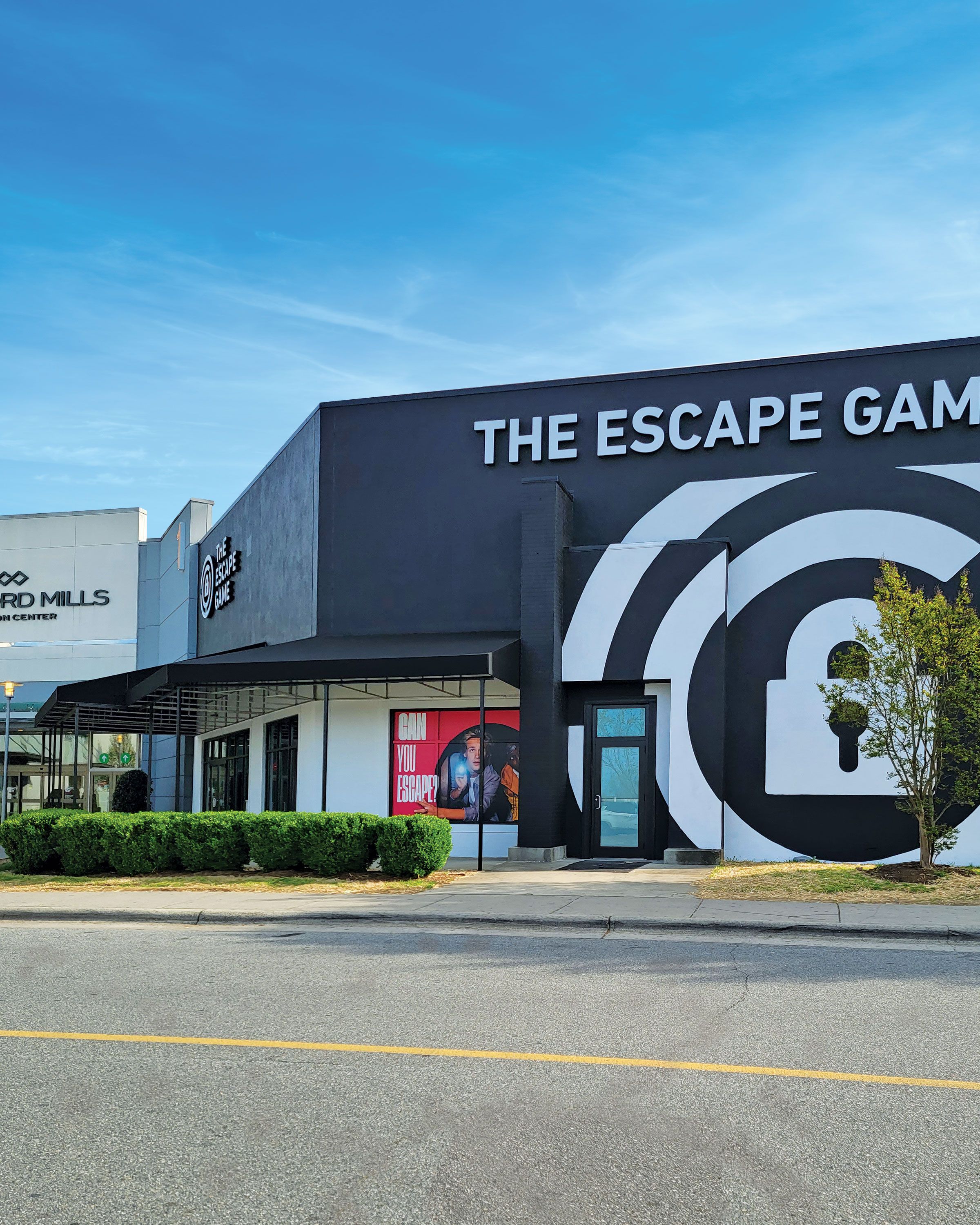 Exterior view of "The Escape Game" building with a bold sign and a promotional poster reading "Can You Escape?"