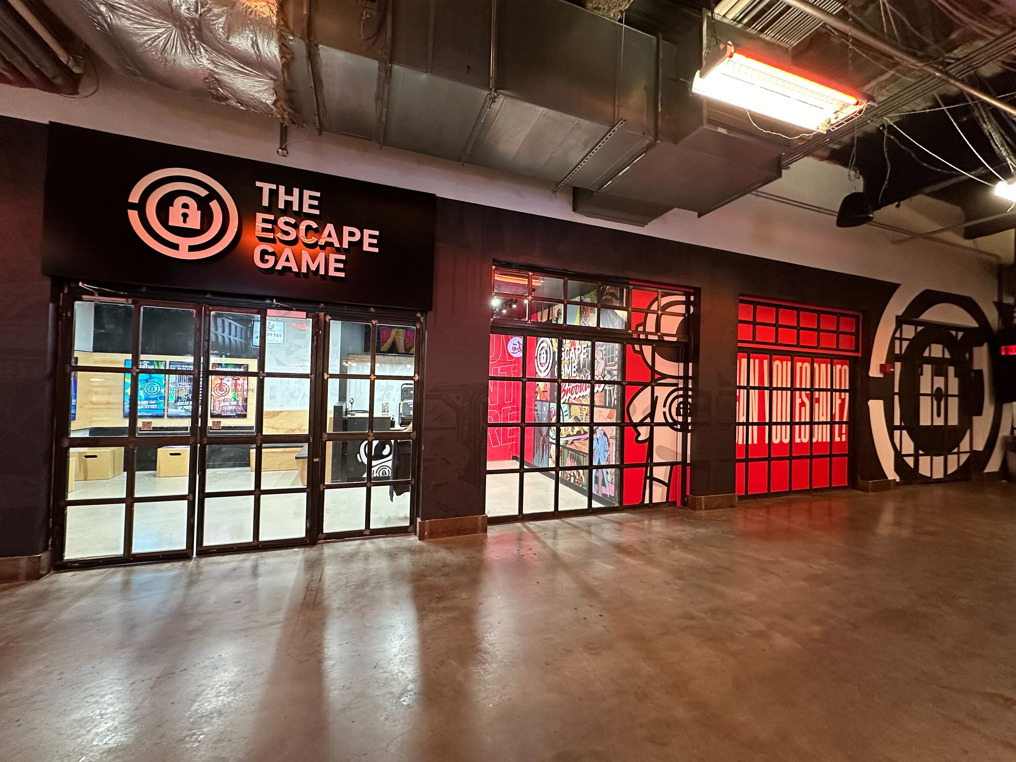 Entrance to "The Escape Game" featuring a large sign and glass doors, with colorful murals on the walls.