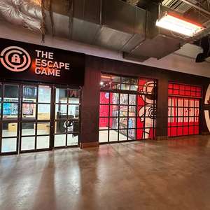 Entrance to "The Escape Game" featuring a large sign and glass doors, with colorful murals on the walls.