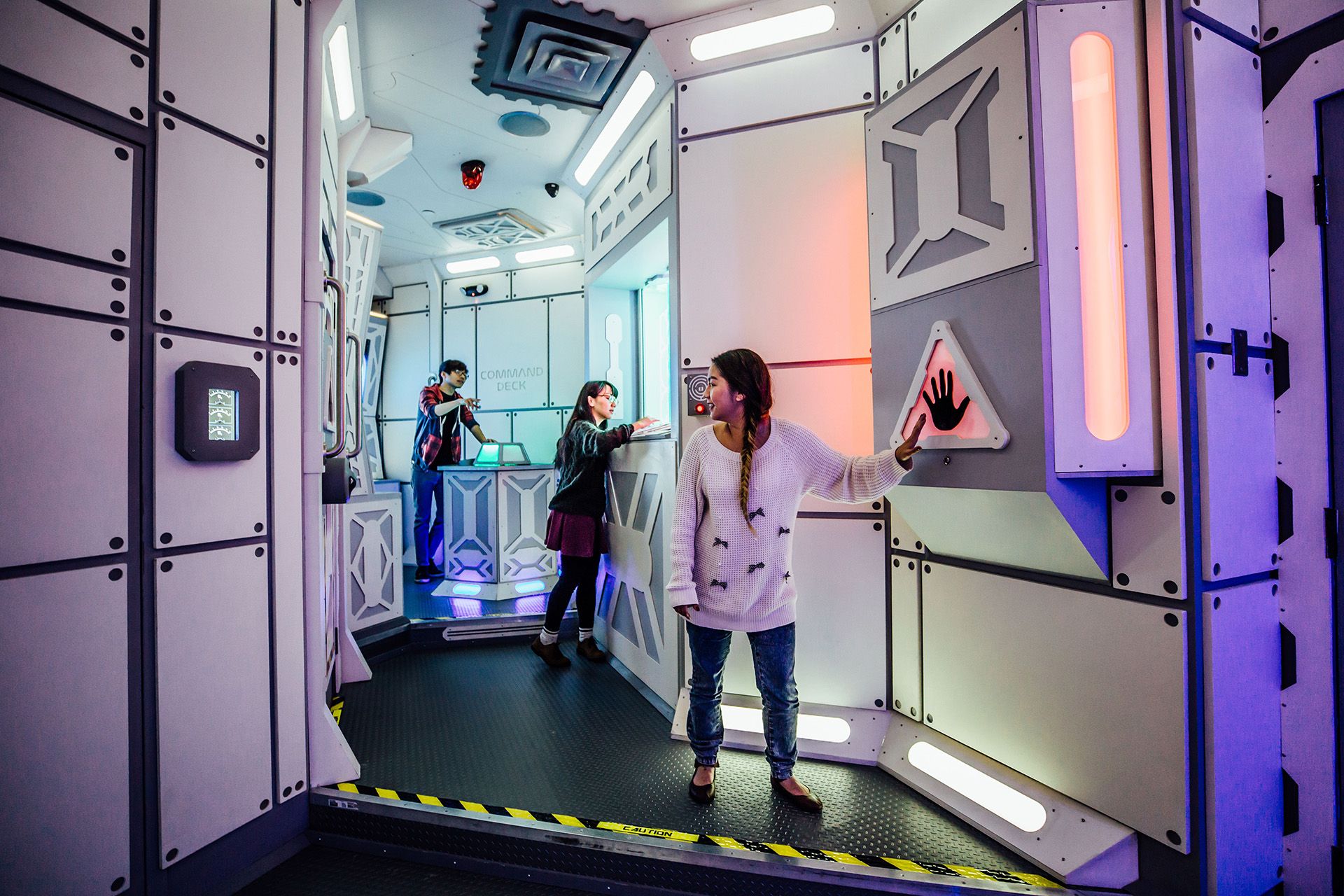 3 people solving clues in a space ship escape room