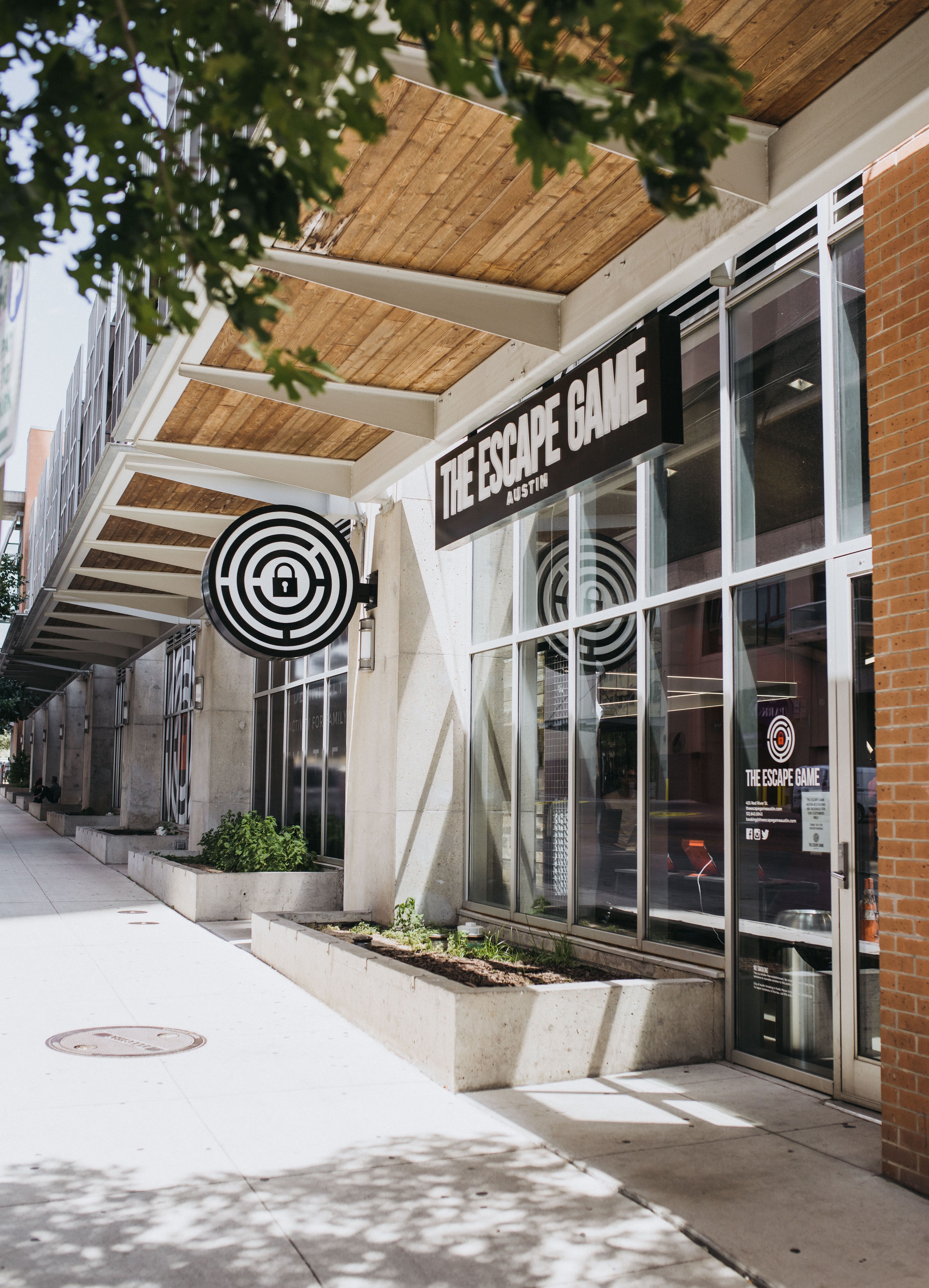 The image shows the exterior of "The Escape Game" in Austin, with large windows, a sign, and a circular logo.