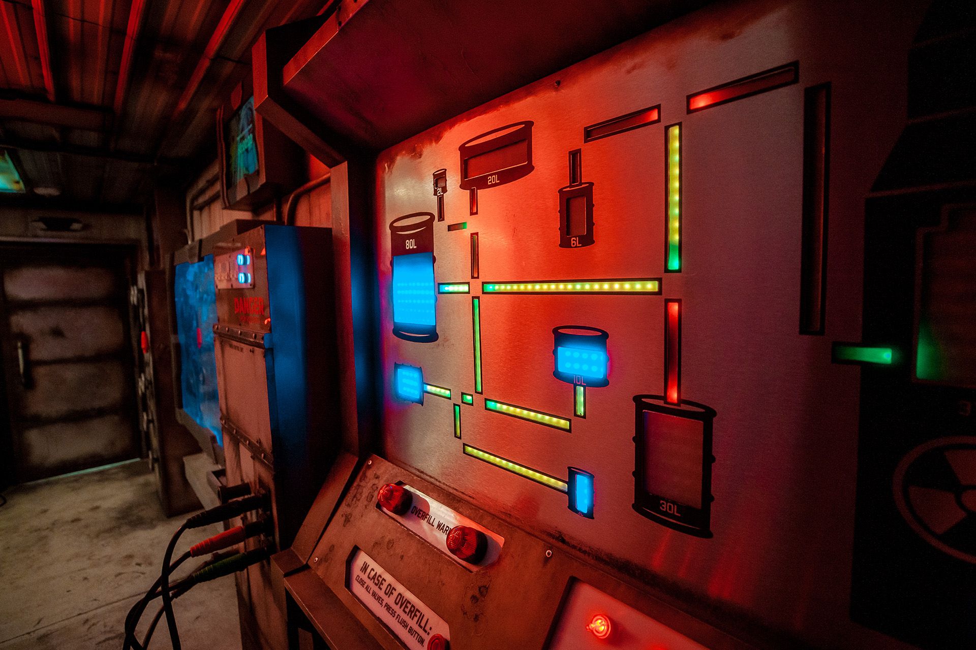 Control panel with colorful lights and buttons, featuring various labeled canisters and wired connections in a dimly lit environment.
