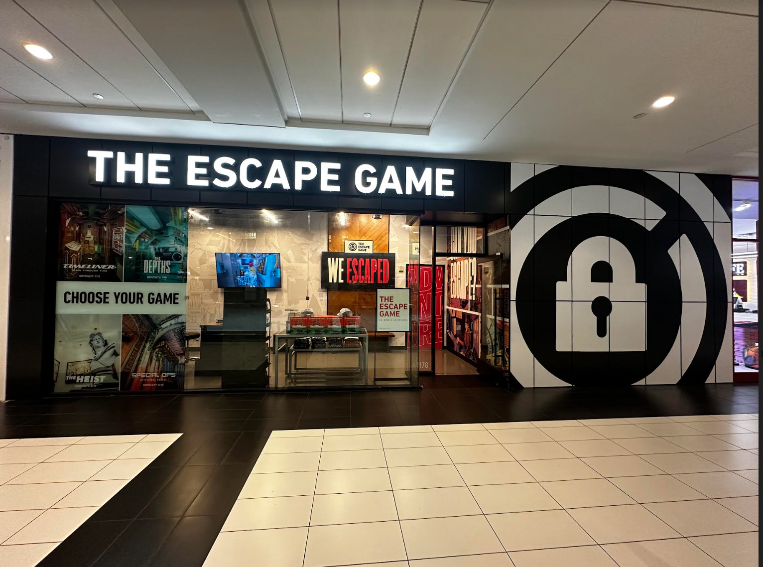 Entrance of "The Escape Game," featuring bold signage, game posters, and a large lock graphic on the left wall.