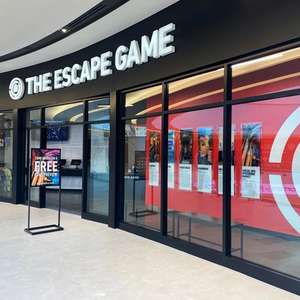 Exterior view of "The Escape Game" location, featuring glass doors, promotional signage, and game information posters.