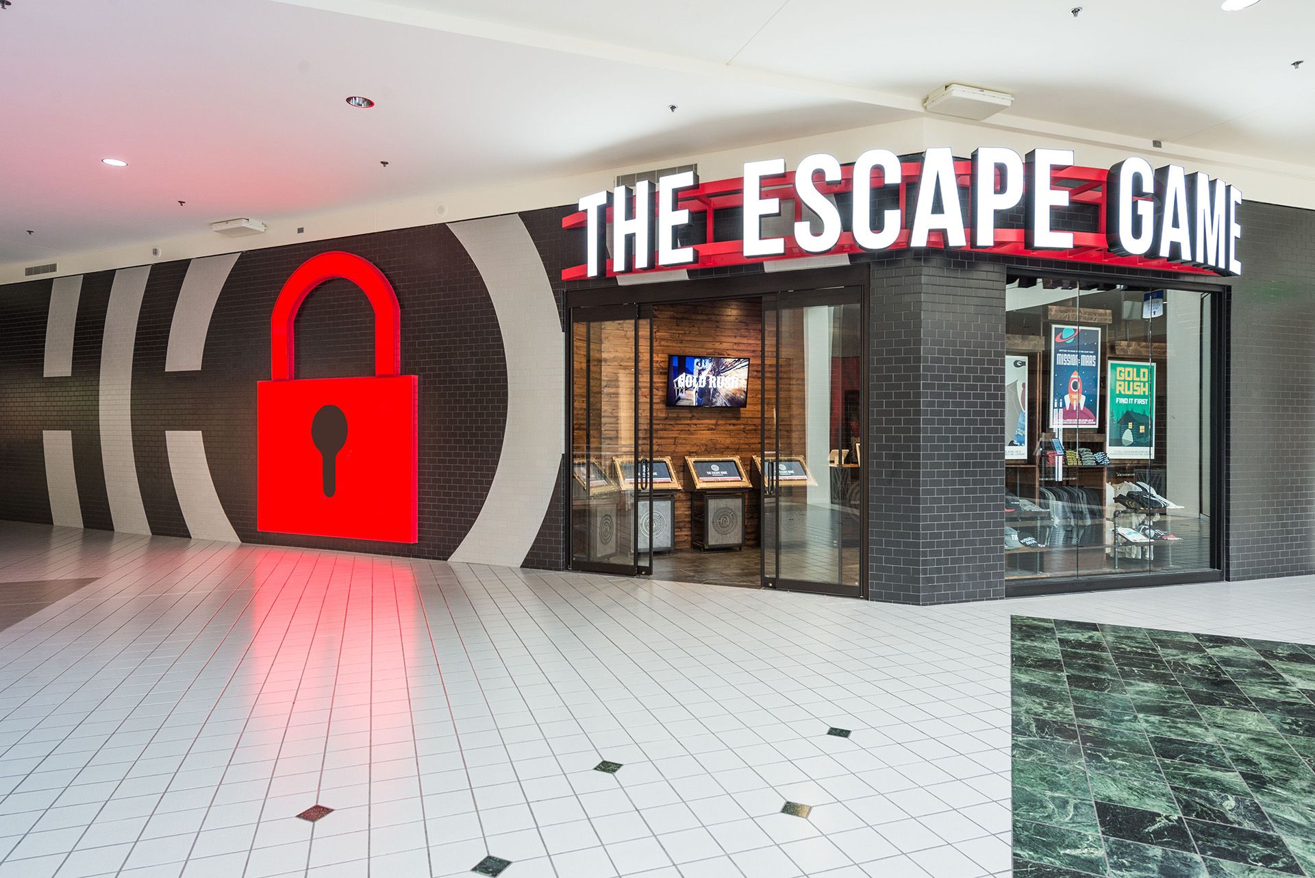 Entrance of "The Escape Game" featuring a large red lock icon and bright signage in a mall setting.
