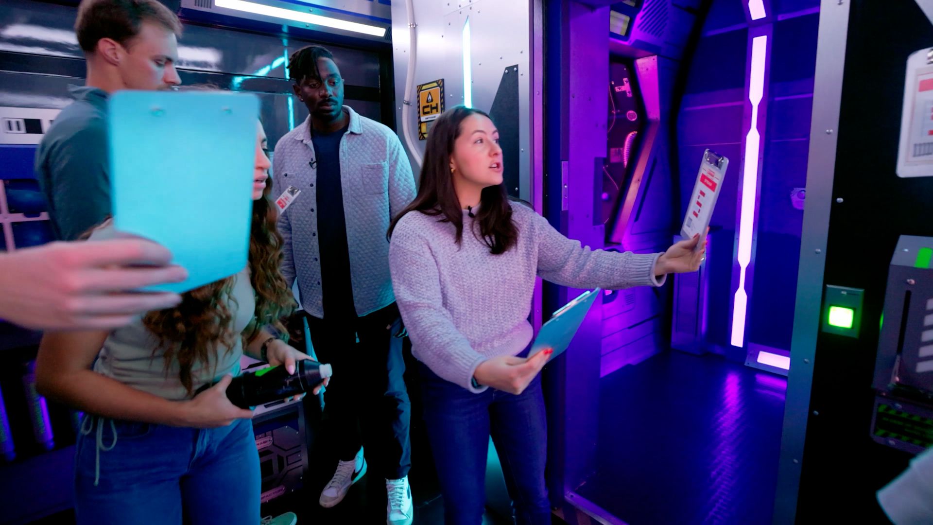 Four people in an escape room holding clipboards