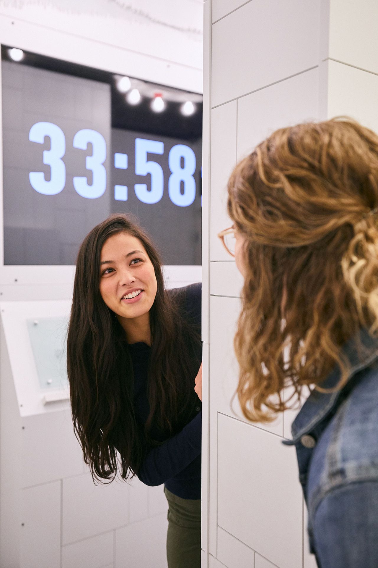 Two women are engaged in conversation through a partition, with a timer displaying 33:58 in the background.