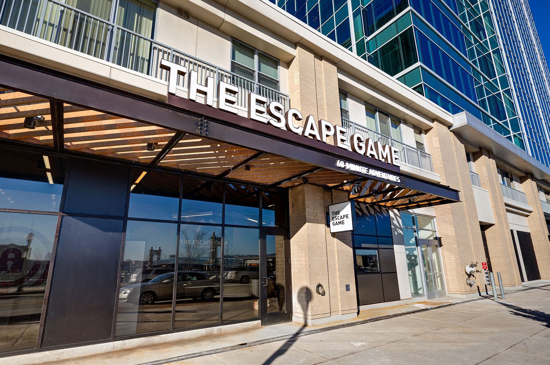 Exterior of "The Escape Game" building, featuring large windows and a modern design, under clear blue skies.