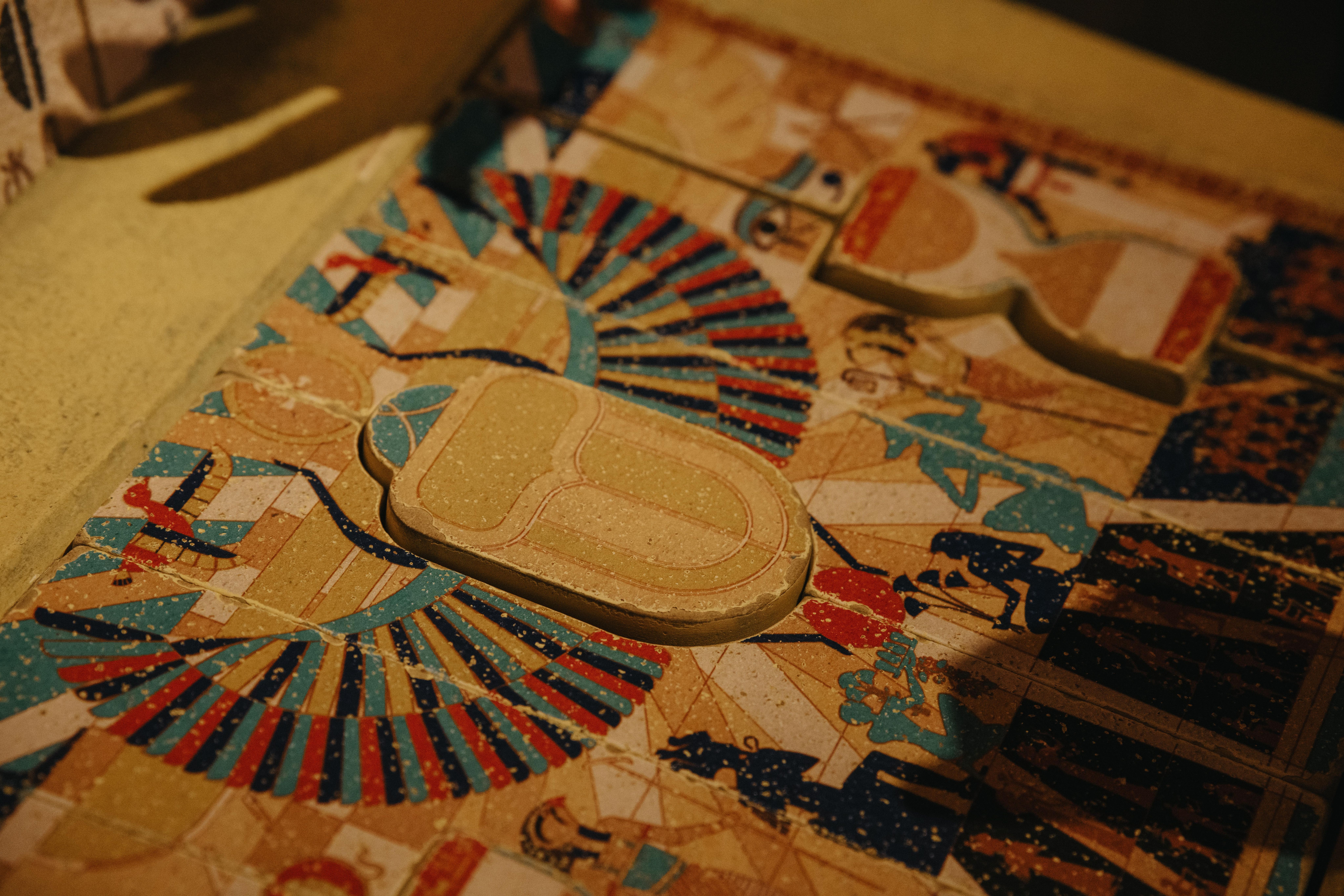 Close-up of a colorful, hieroglyph-covered surface with a carved-out scarab shape and decorative patterns.