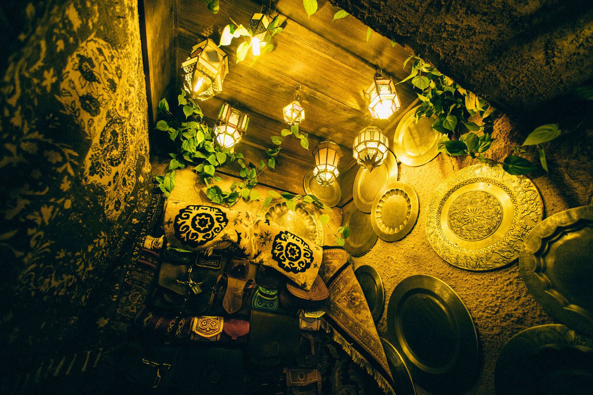 Cozy room filled with patterned textiles, decorative metal plates on the walls, and warm, soft lighting from lanterns.